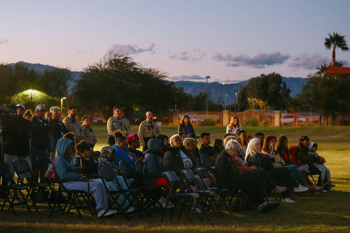 Attendees sit in the fading light during a tree dedication in honor of domestic violence victim ...