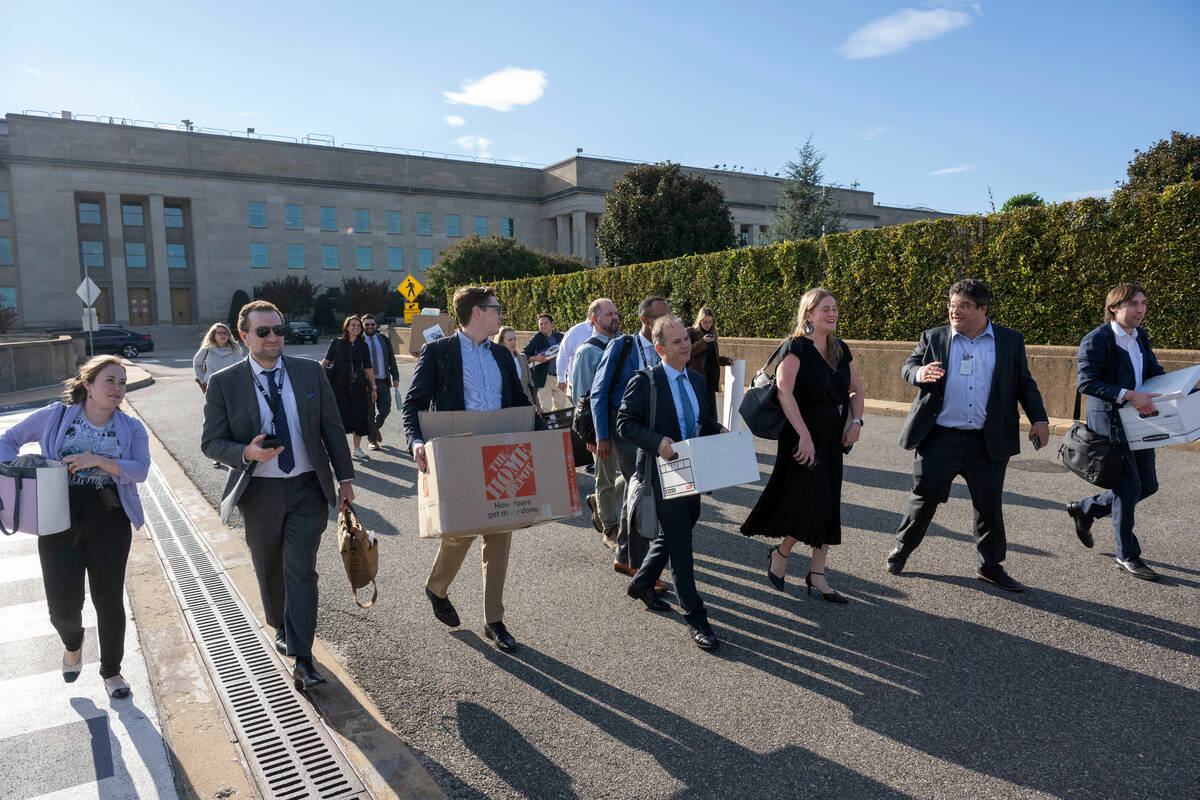 Members of the Pentagon press corp carry their belongings out of the Pentagon after turning in ...