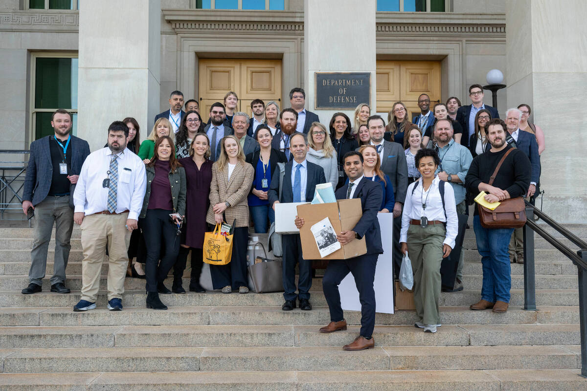 Members of the Pentagon press corp gather for a group photo after turning in their press creden ...