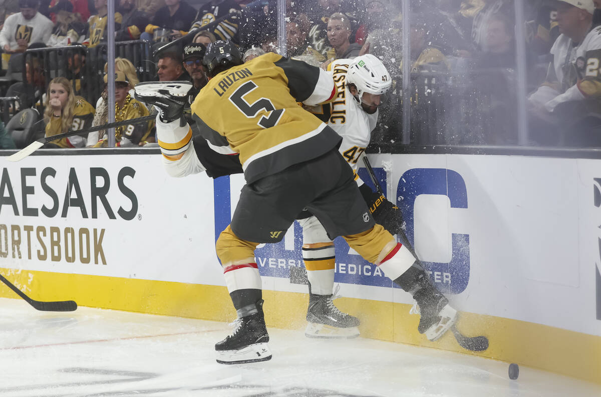 Golden Knights defenseman Jeremy Lauzon (5) takes Boston Bruins center Mark Kastelic (47) to th ...