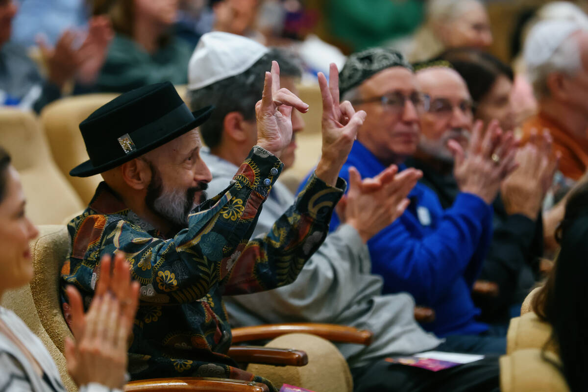 An attendee holds up a peace sign and the American Sign Language sign for “I love you&#x ...
