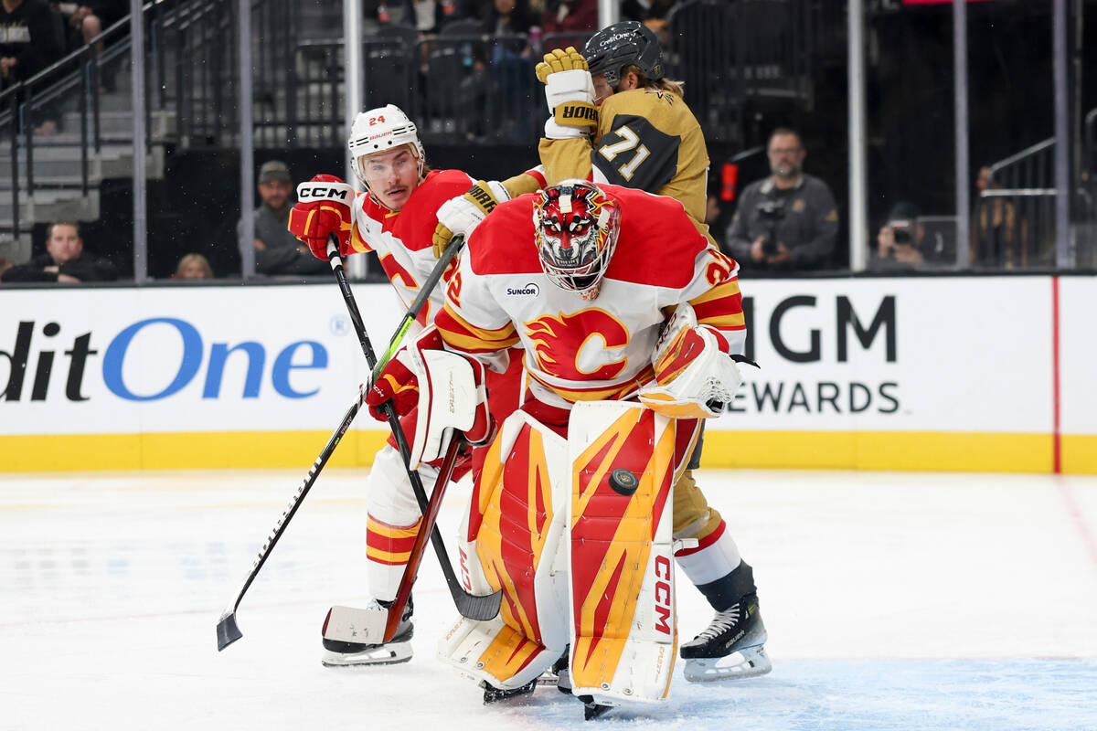 Calgary Flames goaltender Dustin Wolf (32) makes a save in front of defenseman Jake Bean (24) a ...