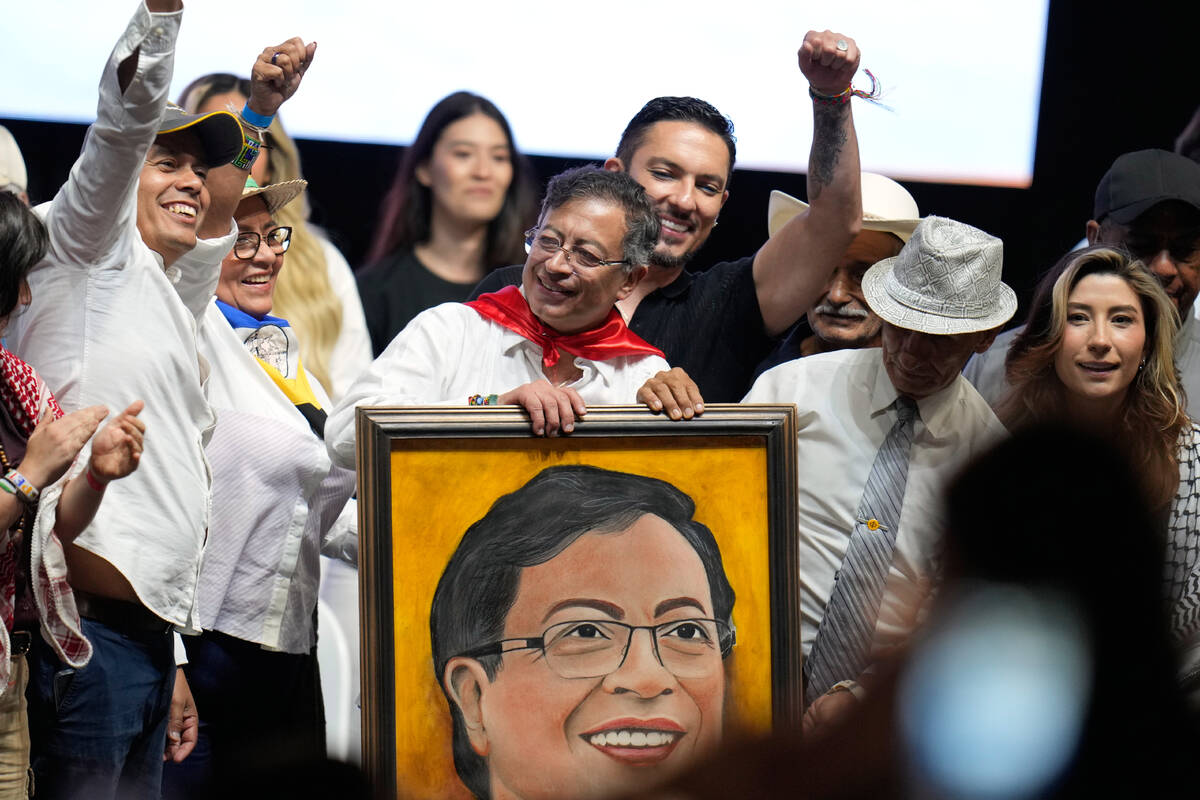 Colombian President Gustavo Petro holds up a portrait given to him by a supporter during a rall ...