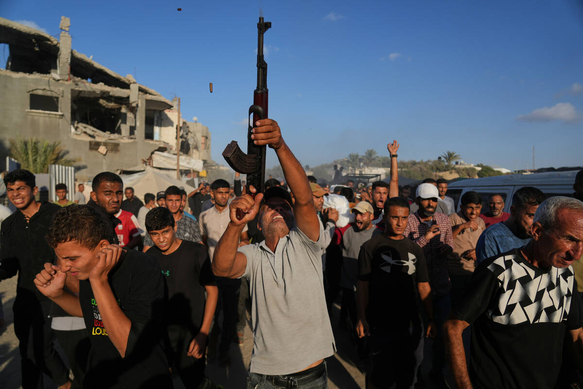 An armed man shoots in the air during the funeral of Palestinians killed by Israeli fire, in De ...