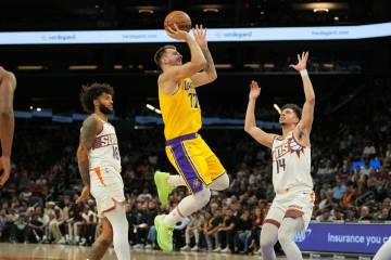 Los Angeles Lakers forward/guard Luka Doncic (77) shoots between Phoenix Suns Isaiah Livers and ...
