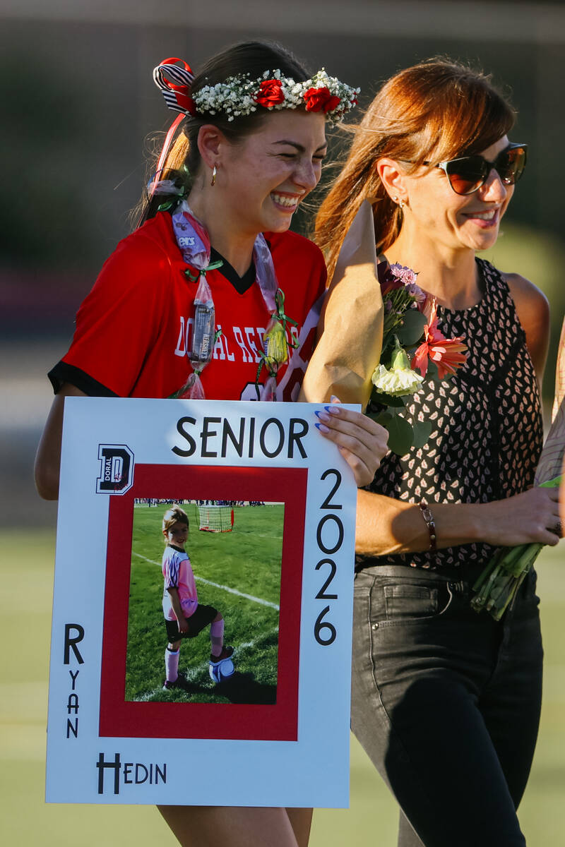 Doral Academy senior Ryan Hedin grins as she makes her way down the field escorted by her paren ...