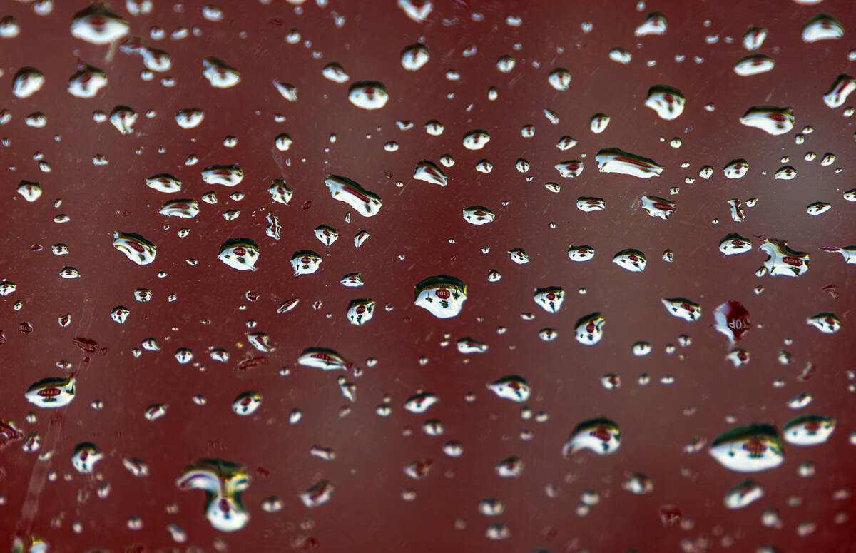Water droplets create an upside down reflection of a stop sign as rain moves through the area o ...