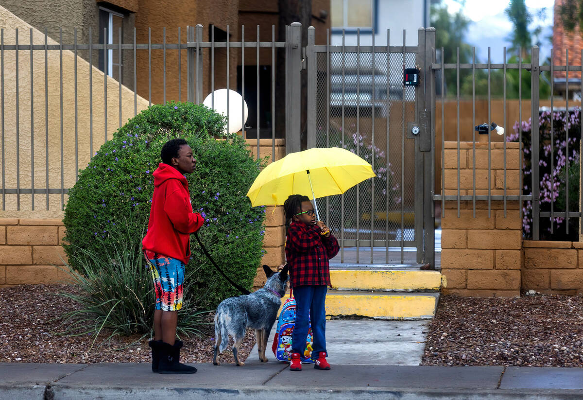 A child waits for her school bus with an adult and dog at her side along North Jones Boulevard ...