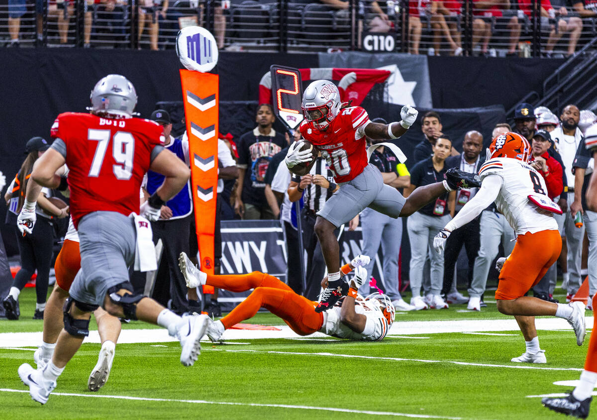 UNLV running back Jaylon Glover (20) leaps over Idaho State Bengals safety Dekker Hagler (14) o ...