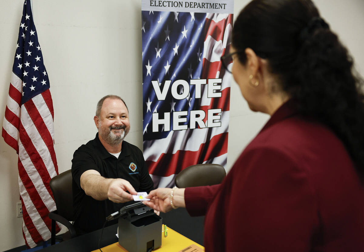 Clark County Election Department spokesperson Dan Kulin, left, helps Lorena Portillo, Clark Cou ...