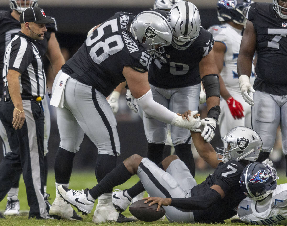 Raiders quarterback Geno Smith (7) is helped up by guard Jackson Powers-Johnson (58) after bein ...