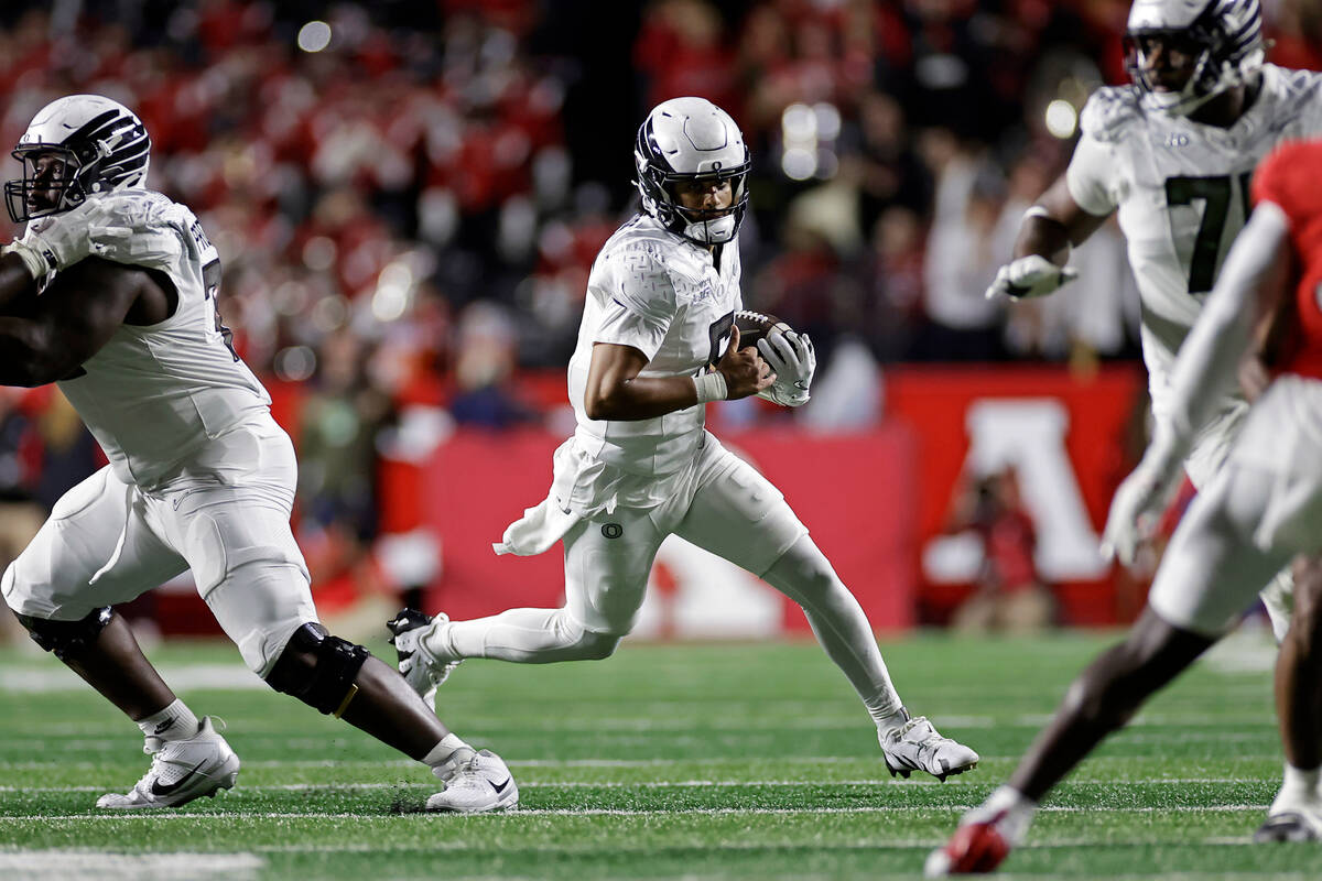 Oregon quarterback Dante Moore, center, runs with the ball during the first half of an NCAA col ...