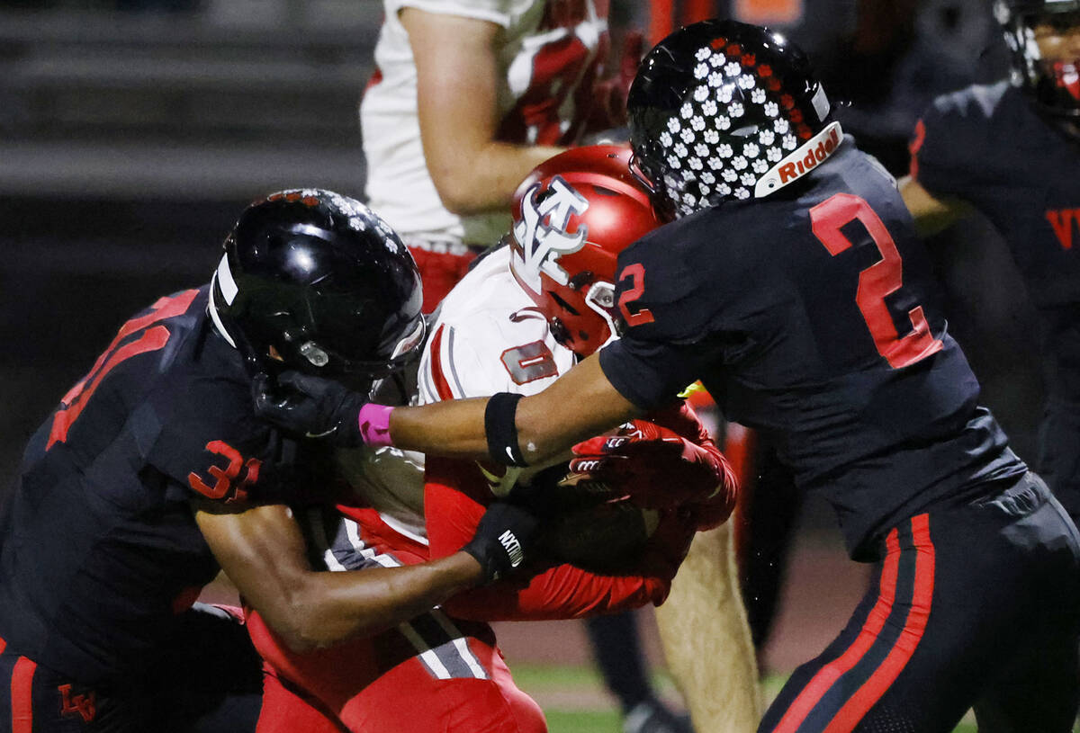 Arbor View's running back Kamareion Bell (0) is sandwiched between Las Vegas High's T ...