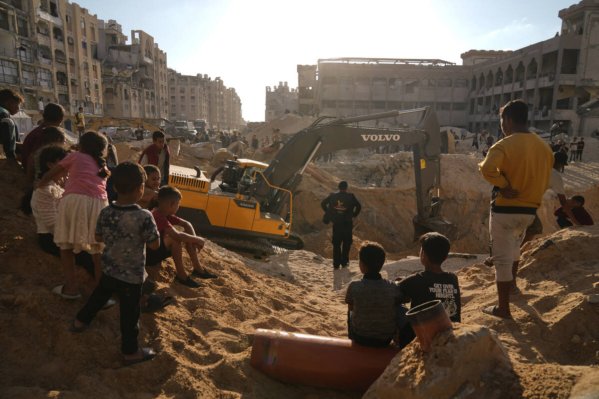 Palestinians watch machinery and some workers from Egypt searching for the bodies of hostages a ...