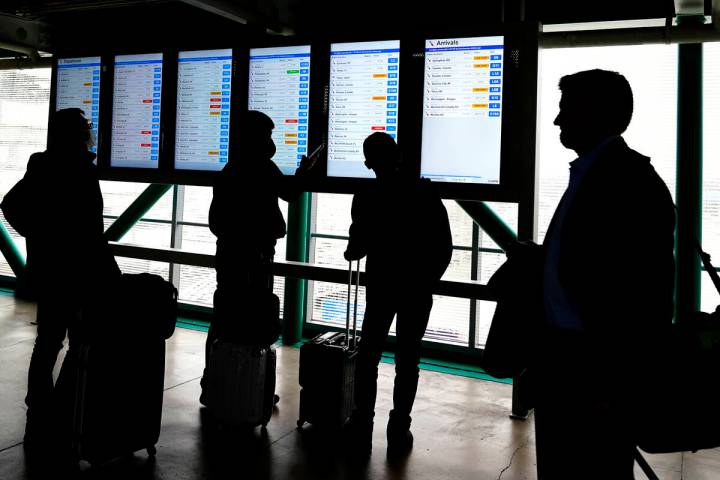 Travelers check American Airlines flight information screens for their flight status at O'Hare ...