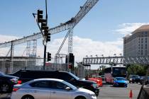 Commuters navigate under light fixtures, part of the Formula One construction, at the intersect ...