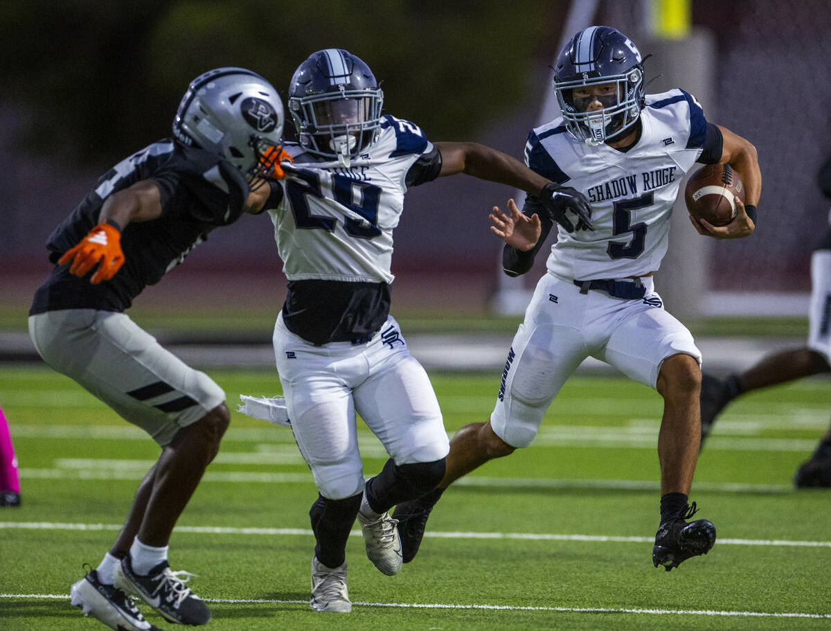 Shadow Ridge quarterback Isaiah Ruiz (5) looks to get around teammate Trevin Young (29) blockin ...
