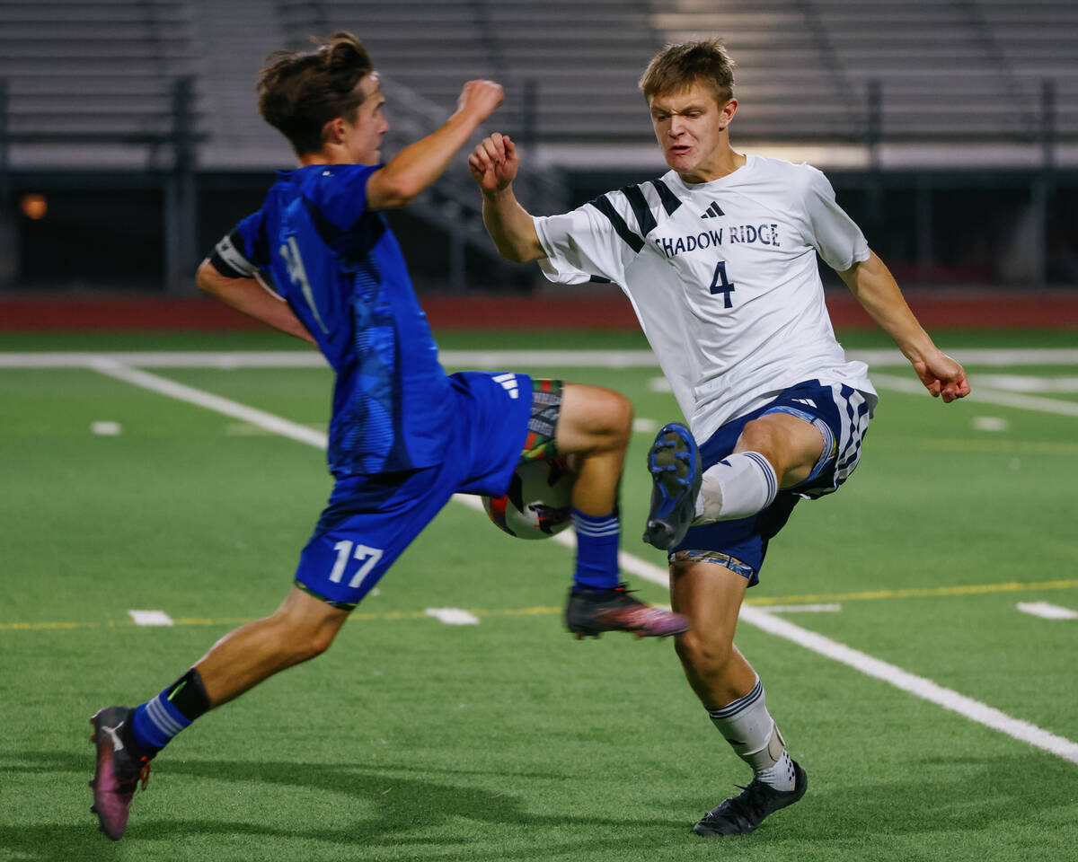 Green Valley midfielder Liam Gilbert (17) rushes to stop a kick by Shadow Ridge defender Carson ...