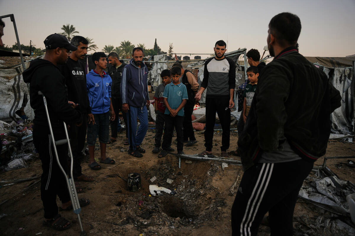 Displaced Palestinians inspect the damage after an Israeli army strike on their tent camp in De ...