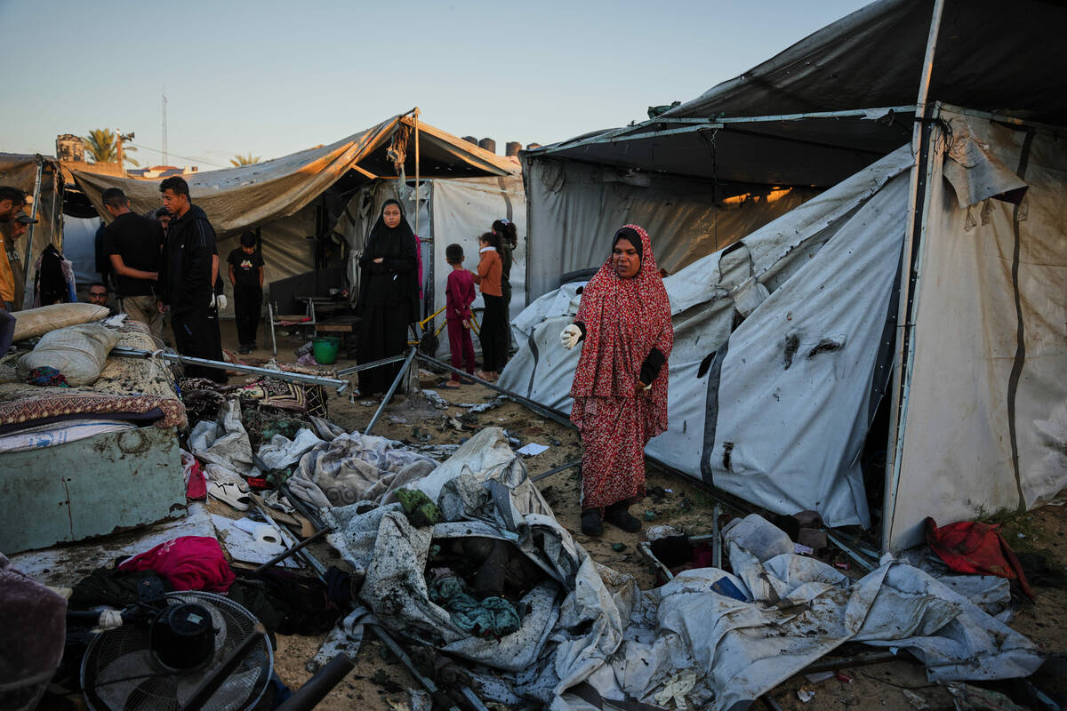 Displaced Palestinians inspect the damage after an Israeli army strike on their tent camp in De ...