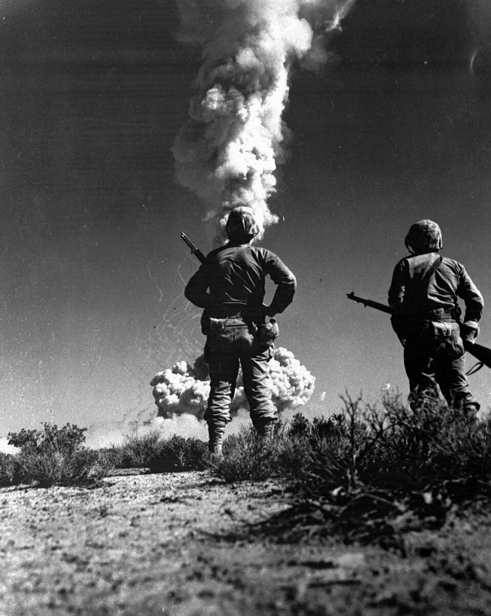 Two soldiers look at an atomic cloud during a nuclear bomb testing in Nevada in this 1952 file ...