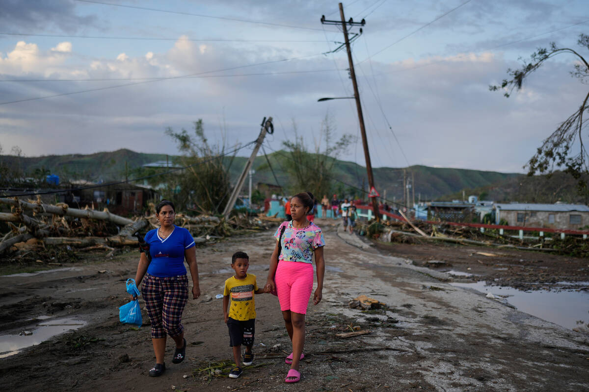 Residents walk in the aftermath of Hurricane Melissa in El Cobre, Cuba, Wednesday, Oct. 29, 202 ...