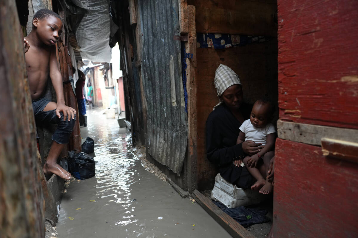 People stay inside a shelter for families displaced by gang violence, flooded by rain brought b ...