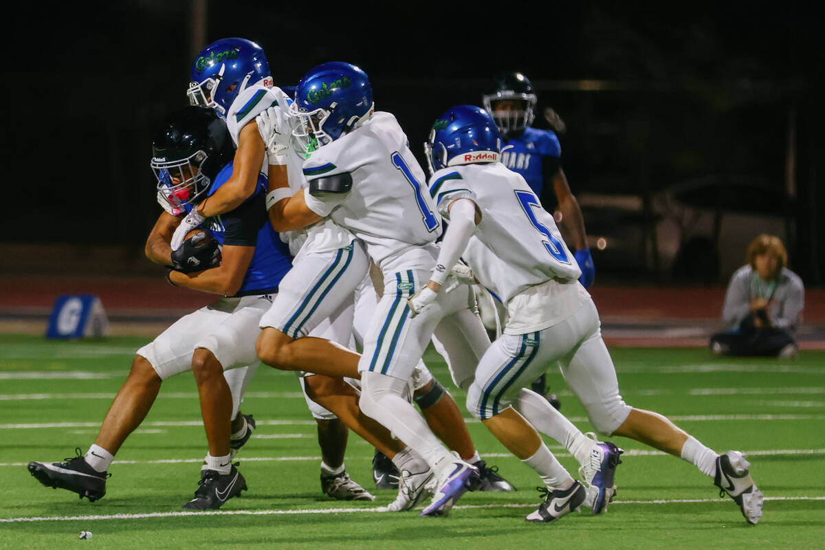 The Green Valley defense overwhelms ballcarrier Desert Pines wide receiver Mario Velasco Fletch ...