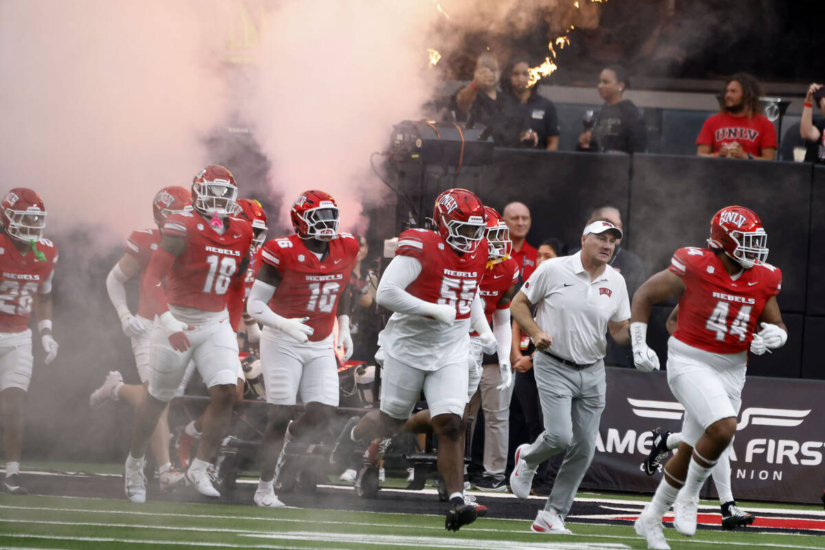 UNLV head coach Dan Mullen, second right, and his players take the field to face Air Force Falc ...