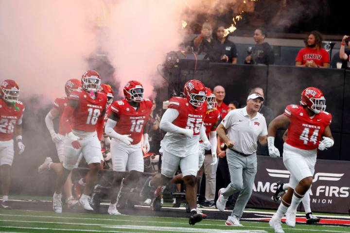 UNLV head coach Dan Mullen, second right, and his players take the field to face Air Force Falc ...