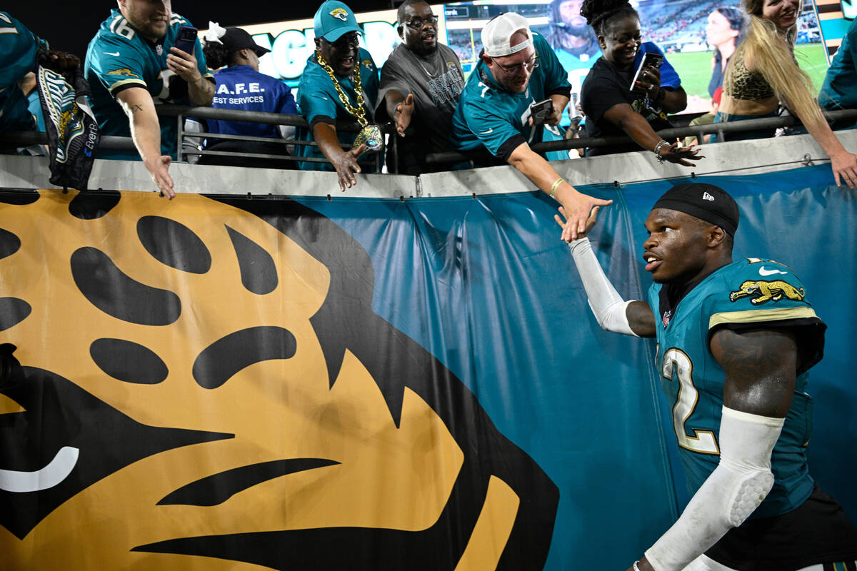 Jacksonville Jaguars wide receiver Travis Hunter (12) slaps hands with fans in the stands after ...
