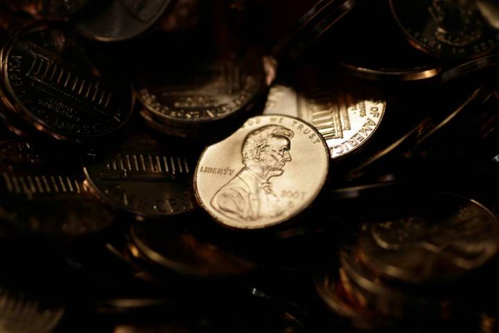 FILE - A lone penny is illuminated in a bin of completed pennies at the U.S. Mint in Denver on ...