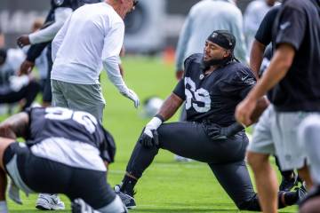 Raiders head coach Pete Carroll chats with a defensive tackle Adam Butler (69) as they stretch ...