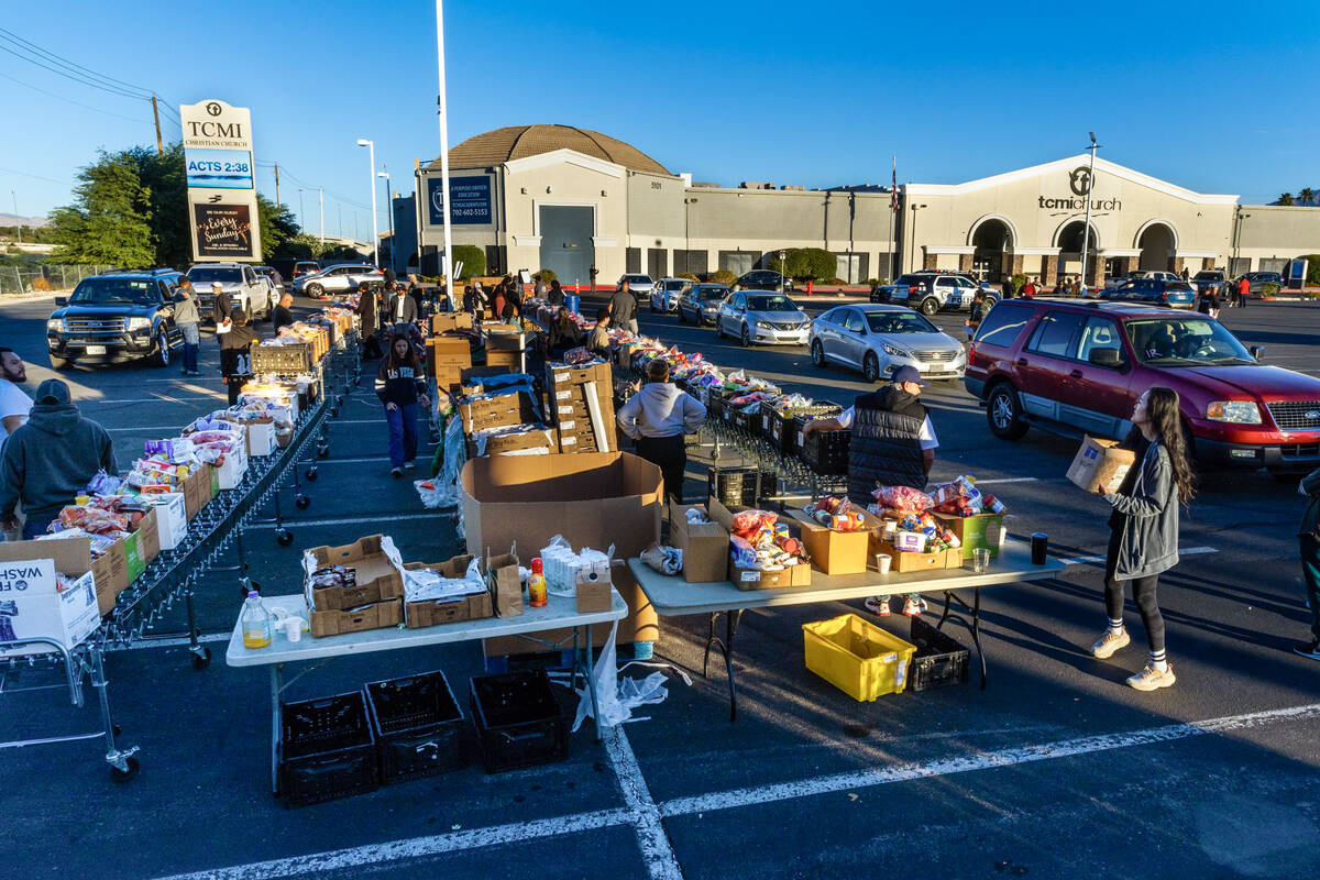 Volunteers pack and distribute food boxes for people waiting in a line of cars at TCMI Church d ...