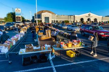 Volunteers pack and distribute food boxes for people waiting in a line of cars at TCMI Church d ...
