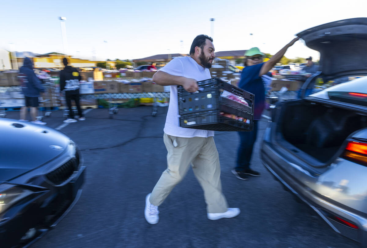 Volunteer Ernesto Rivas loads a food box into the trunk of a car during the Three Square Food B ...