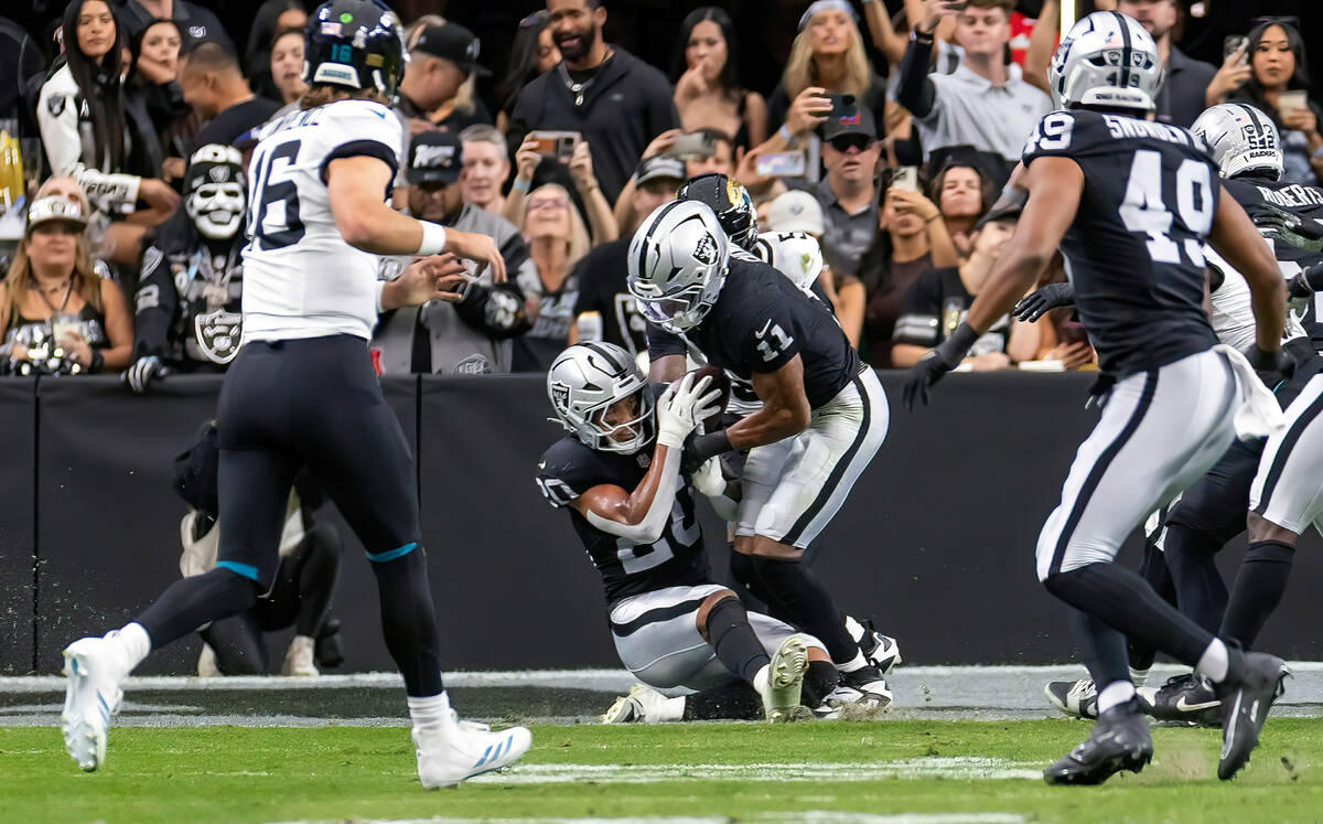 Raiders safety Isaiah Pola-Mao (20) makes and interception with assistance from Raiders safety ...