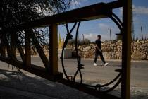 A Palestinian man walks past a gate set up by Israeli authorities at the entrance of the West B ...