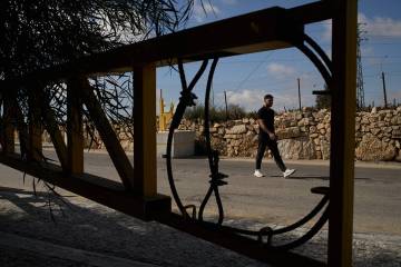 A Palestinian man walks past a gate set up by Israeli authorities at the entrance of the West B ...