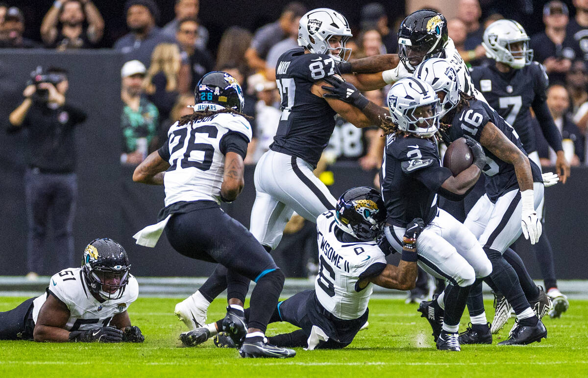 Raiders running back Ashton Jeanty (2) breaks through the line and a tackle attempt by Jacksonv ...