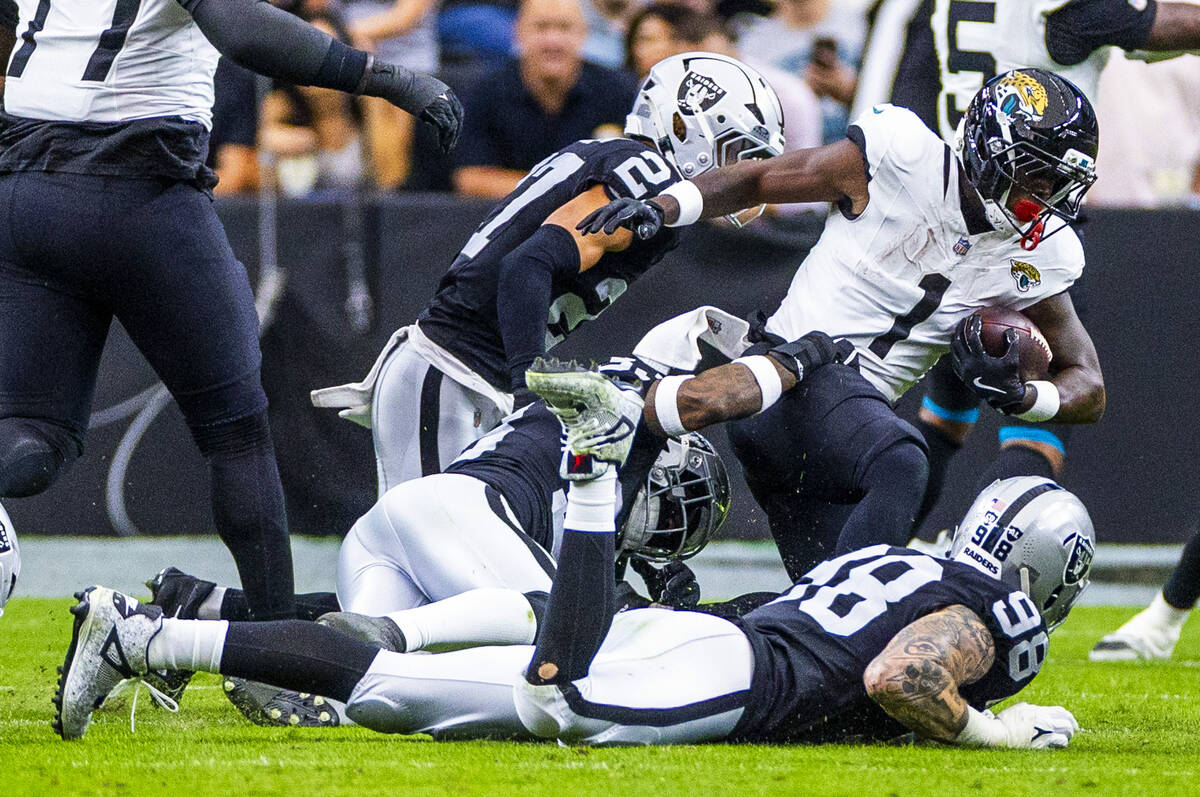 Raiders defensive end Maxx Crosby (98) and Raiders linebacker Jamal Adams (33) help stop runnin ...