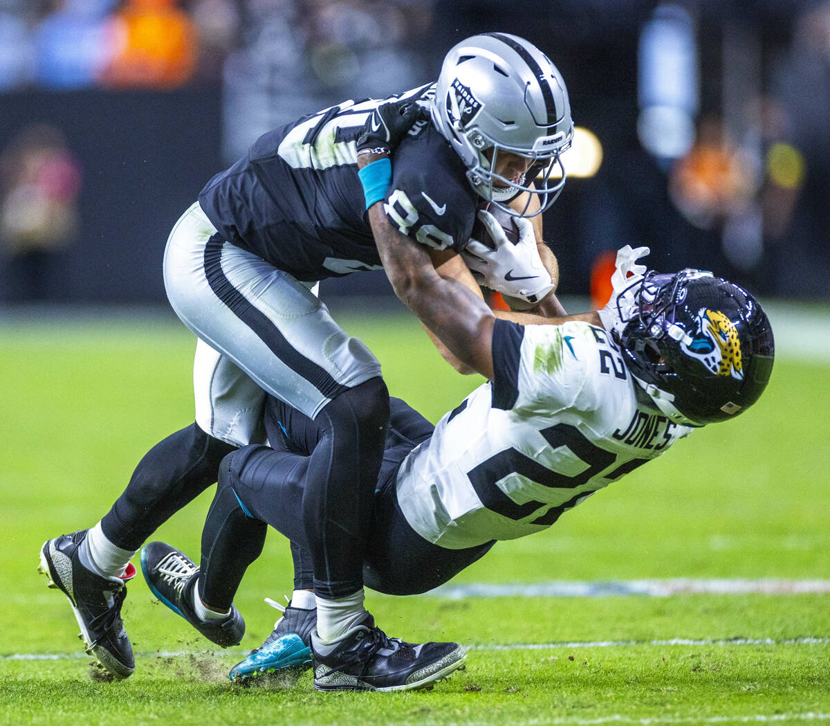 Raiders tight end Brock Bowers (89) drives Jacksonville Jaguars cornerback Jarrian Jones (22) o ...