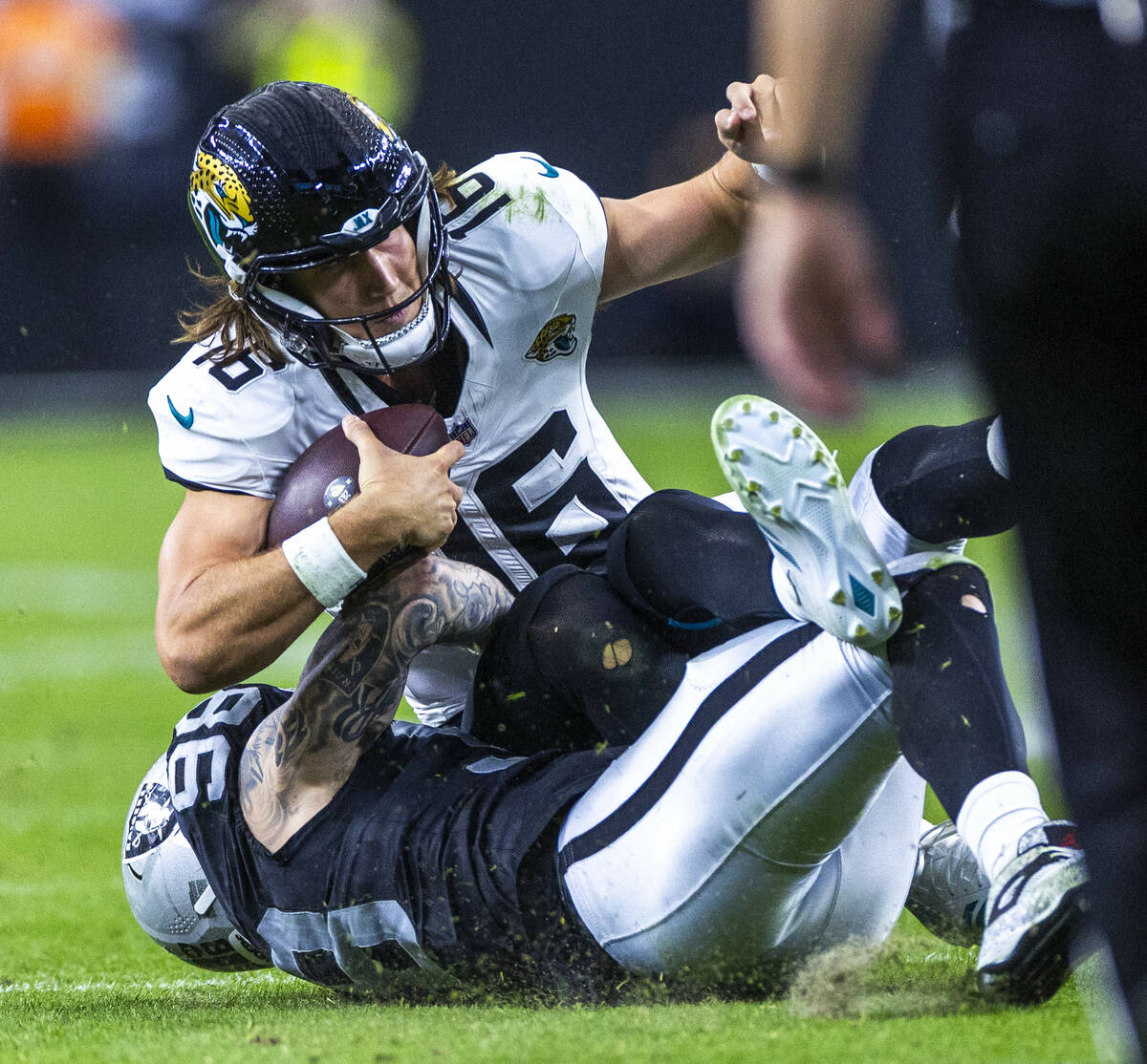 Jacksonville Jaguars quarterback Trevor Lawrence (16) is sacked by Raiders defensive end Maxx C ...