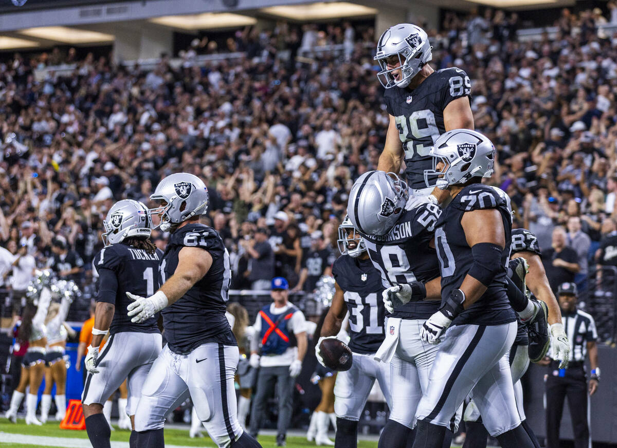 Raiders tight end Brock Bowers (89) is lifted up by Raiders center Jackson Powers-Johnson (58) ...