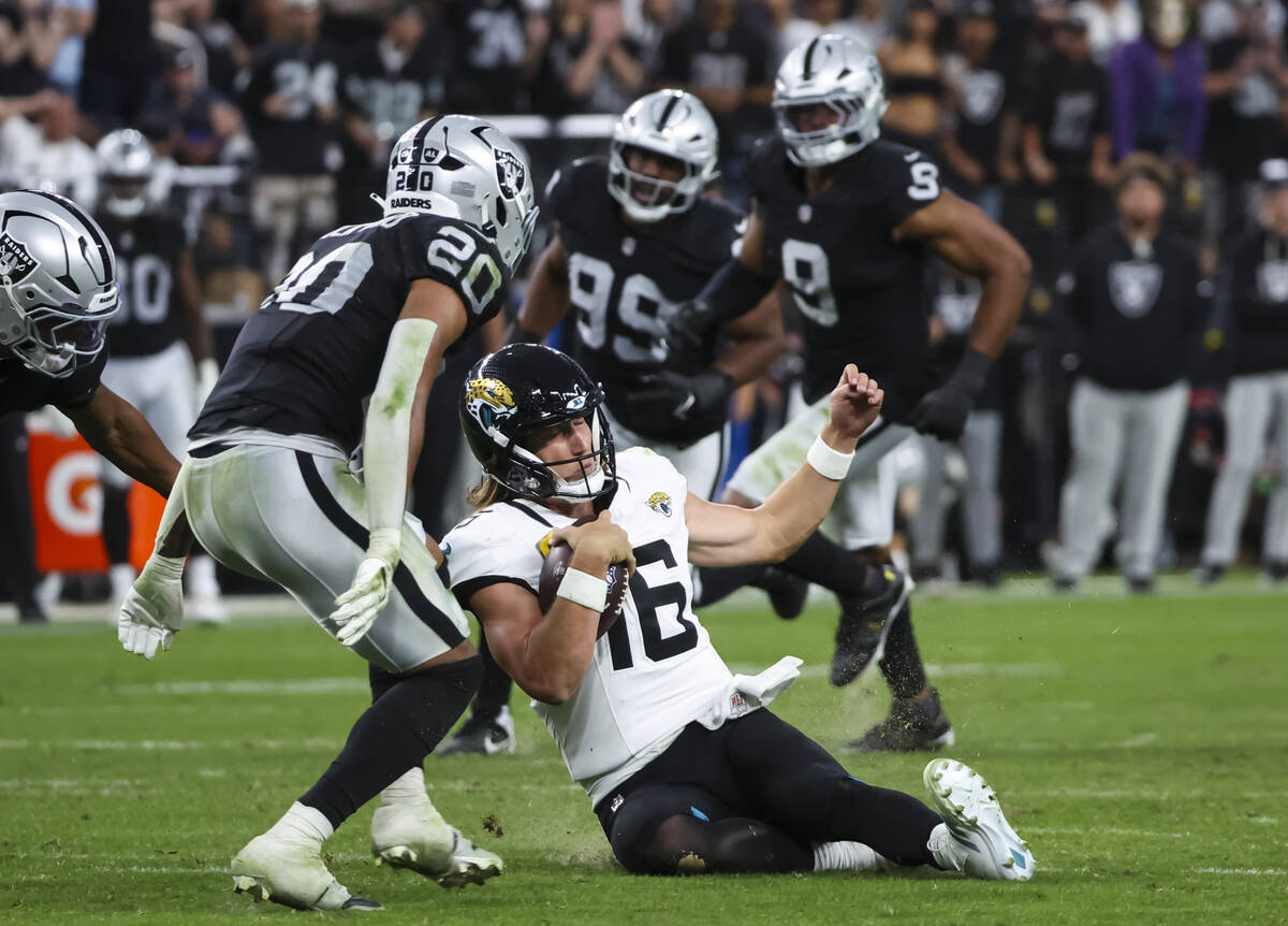 Jacksonville Jaguars quarterback Trevor Lawrence (16) slides to the grass under pressure from R ...