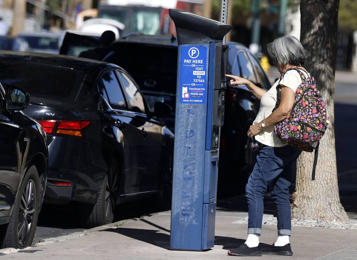 A woman pays for her parking space on Third Street near the Regional Justice Center on Monday, ...