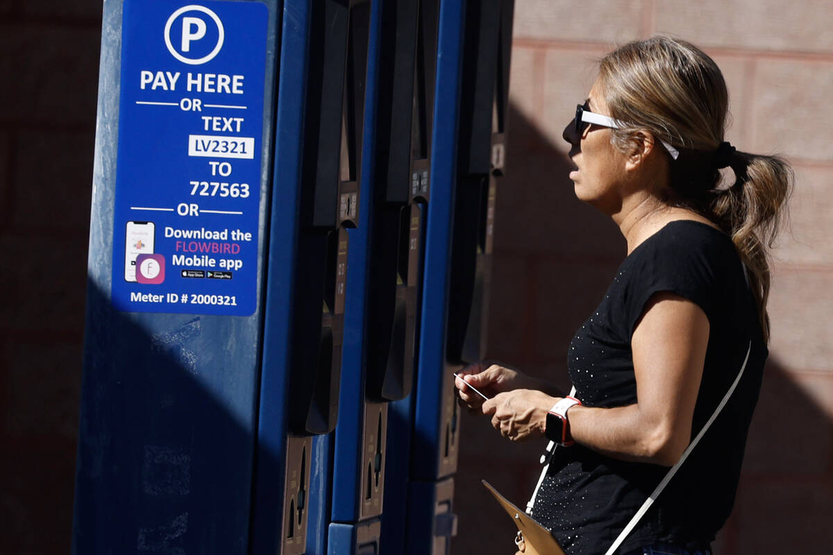 A woman pays for her parking space at a city-operated parking lot on Third Street near the Regi ...
