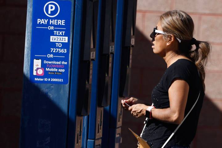 A woman pays for her parking space at a city-operated parking lot on Third Street near the Regi ...