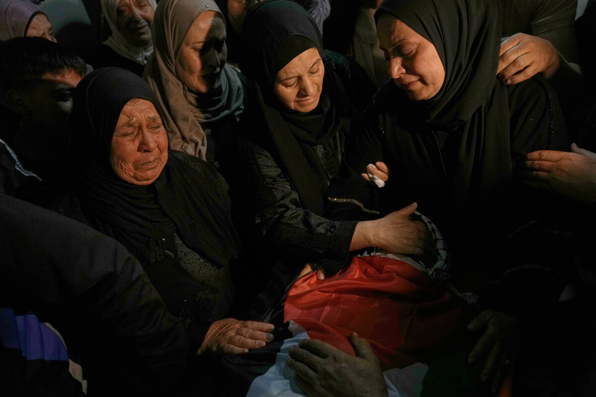 Palestinian women mourn over the body of Jamil Hanani, 17, who, according to health authorities ...