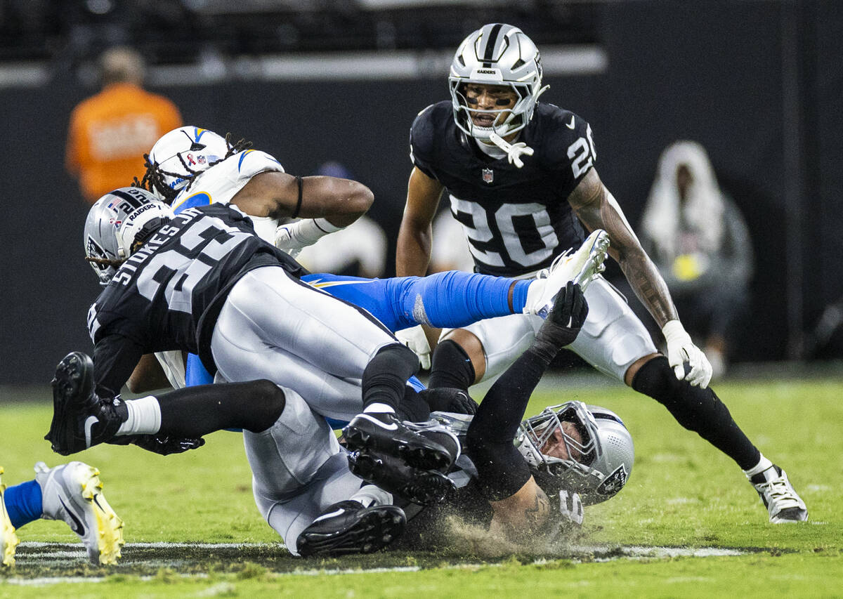 Raiders safety Isaiah Pola-Mao (20) and defensive end Maxx Crosby (98) team up to stop Los Ange ...